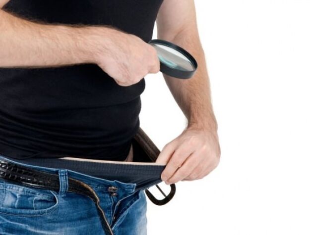 A man looks down at his pants and wants to enlarge his penis